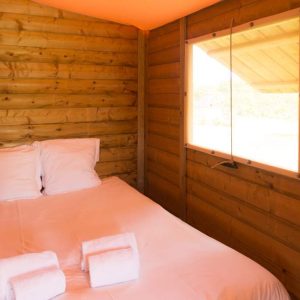 Cabane en bois cosy avec lit double et vue sur la nature en Aquitaine.