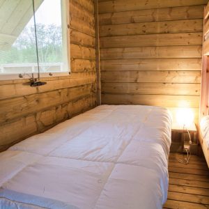 Cabane en bois avec lits superposés et lumière douce, idéale pour un séjour insolite.