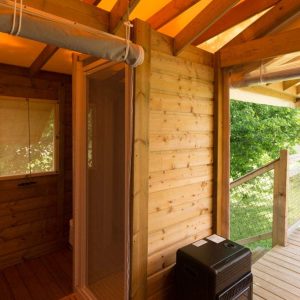 Cabane en bois avec terrasse, offrant une vue sur la nature verdoyante.