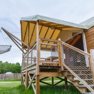 Hébergement insolite en Aquitaine : tente sur pilotis avec un hamac suspendu.
