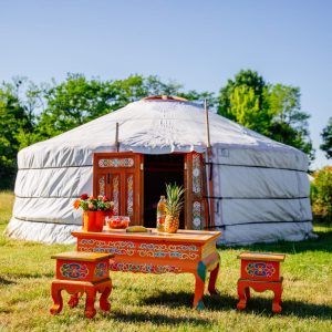 Yourte colorée en Aquitaine, avec une table décorée et des chaises vives en extérieur.