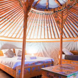 Yourte colorée avec lit douillet et décor traditionnel, située en Aquitaine.