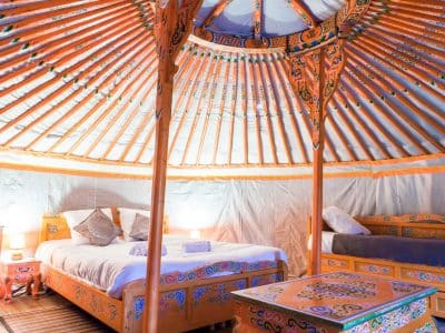 Yourte colorée avec lit douillet et décor traditionnel, située en Aquitaine.
