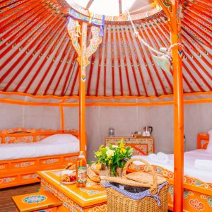 Yourte colorée en Aquitaine, avec des lits en bois et une décoration traditionnelle.