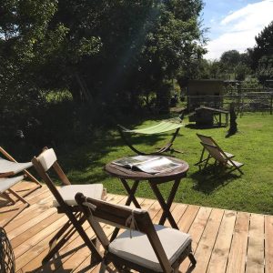 Hébergement insolite en Basse-Normandie, terrasse en bois avec hamac et chaises.