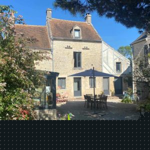 Hébergement insolite en Basse-Normandie, maison en pierre avec jardin fleuri et terrasse.