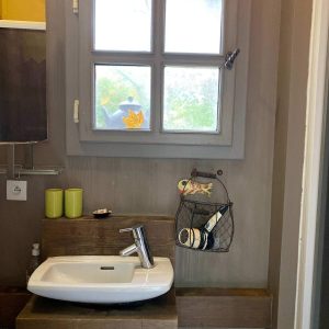 Salle de bain dun hébergement insolite en Basse-Normandie, avec un lavabo moderne et fenêtre.