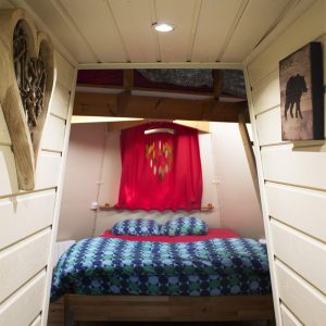 Cabane cosy en Île-de-France, lit douillet avec draps colorés et décoration en bois.