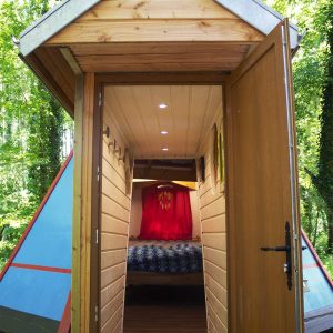 Cabane insolite en bois avec une entrée colorée et un intérieur chaleureux.