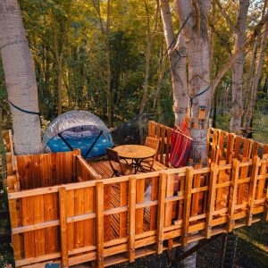 Cabane dans les arbres en Île-de-France, avec terrasse en bois et hamac.