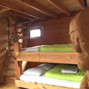 Cabane en bois avec lits superposés et sculpture en bois, ambiance chaleureuse.
