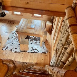 Cabane en bois avec un intérieur chaleureux et un tapis en peau de vache.