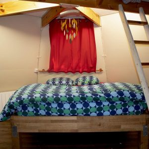 Chalet insolite en Île-de-France avec un lit coloré et une échelle en bois.