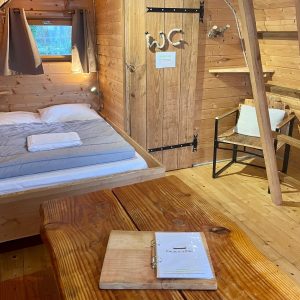 Chalet en bois cosy avec lit double et table en bois, ambiance chaleureuse.