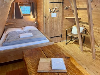 Chalet en bois cosy avec lit double et table en bois, ambiance chaleureuse.