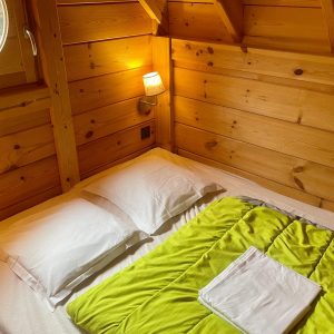 Chalet en bois cosy avec literie confortable et lumière douce, idéal pour un séjour relaxant.