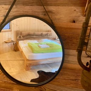 Hébergement insolite en Auvergne : chambre en bois avec lit moderne et décor chaleureux.