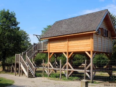 Cabane perchée en bois, accessible par un escalier, au cœur de la nature en Auvergne.