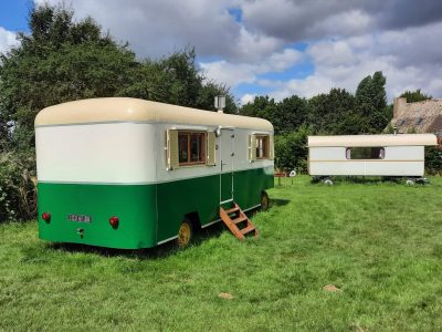 Caravane vintage colorée dans un jardin verdoyant, idéale pour un séjour insolite.