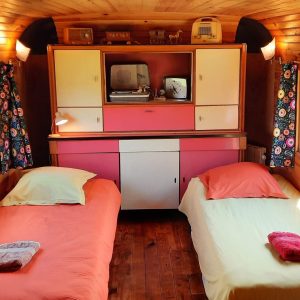 Hébergement insolite : une chambre vintage avec deux lits et décor coloré en bois.