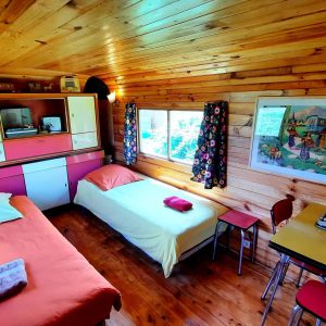 Chalet en bois chaleureux avec lits simples et décor coloré, idéal pour un séjour unique.