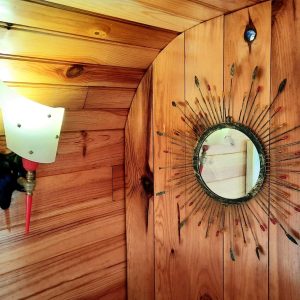 Hébergement insolite en bois avec un miroir décoratif et une lampe vintage.
