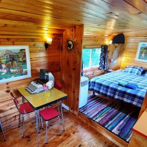 Cabane en bois cosy avec lit double, décor coloré et vue sur la nature.