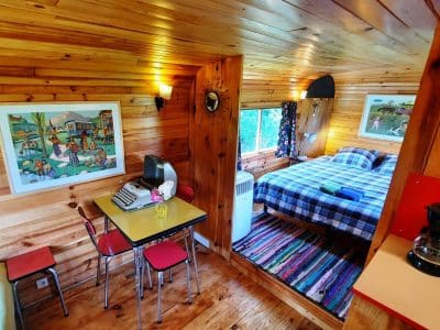 Cabane en bois cosy avec lit double, décor coloré et vue sur la nature.