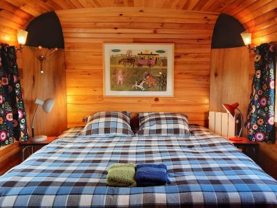 Chalet en bois chaleureux avec lit à carreaux et décor coloré. Parfait pour un séjour insolite.