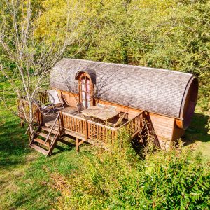 Cabane en bois en Aquitaine, avec terrasse en bois entourée de verdure.