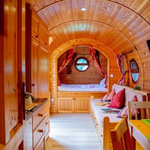 Hébergement insolite en Aquitaine : roulotte en bois avec intérieur chaleureux et fenêtres rondes.