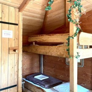 Cabane en bois avec lits superposés et décoration végétale chaleureuse.