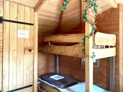 Cabane en bois avec lits superposés et décoration végétale chaleureuse.