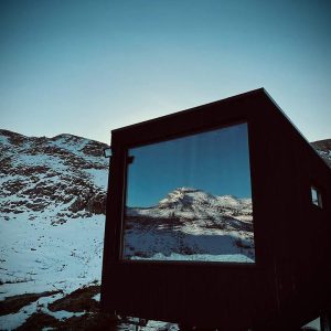 Cabane moderne en bois avec grande fenêtre, vue sur montagnes enneigées en Aquitaine.