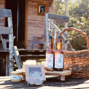 Cabane en bois en Auvergne-Rhône-Alpes, avec panier et boissons sur la table.