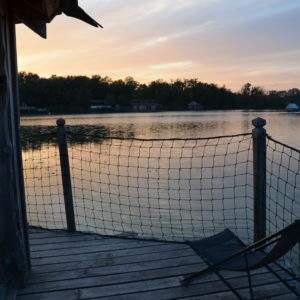 Cabane flottante au bord dun lac, avec une vue paisible au coucher du soleil.