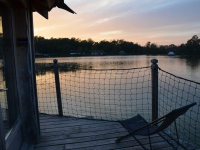 Cabane flottante au bord dun lac, avec une vue paisible au coucher du soleil.