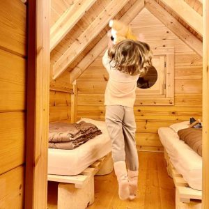 Cabane en bois dans les Alpes, enfant sautant joyeusement entre les lits.
