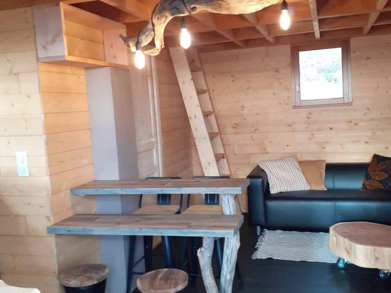 Chalet en bois chaleureux avec un coin salon et des luminaires en bois.