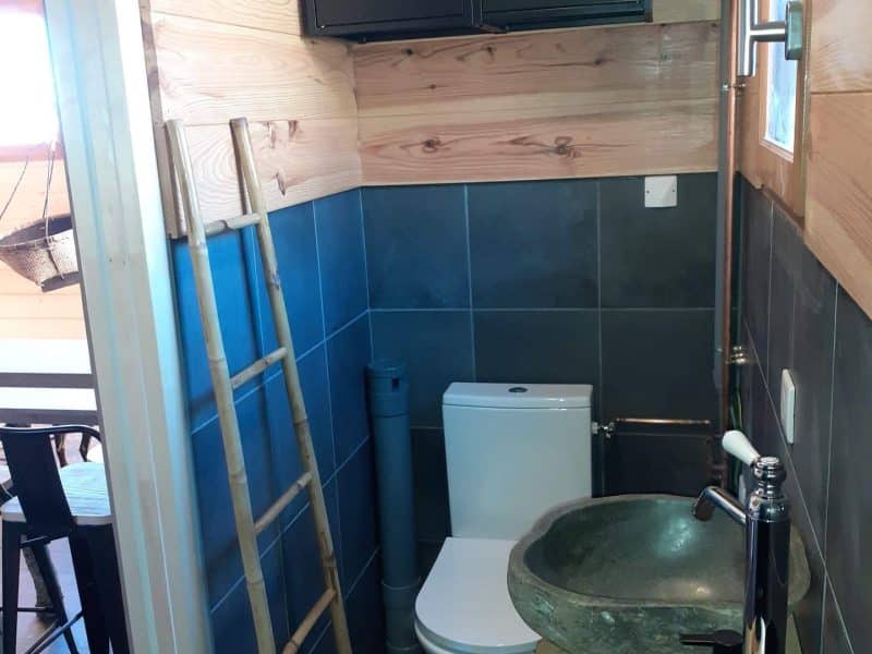 Salle de bain moderne dans un chalet en bois, avec lavabo en pierre et décor chaleureux.