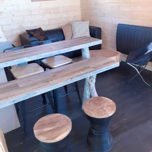 Hébergement insolite en bois avec table en bois brut et chaises modernes.