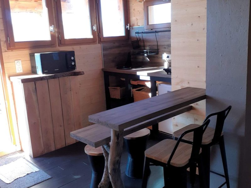 Chalet en bois avec cuisine moderne et table en bois naturel. Ambiance chaleureuse.