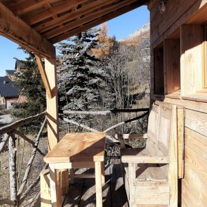 Cabane en bois avec terrasse, offrant une vue sur la nature environnante.