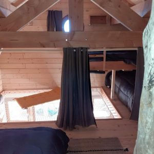 Cabane en bois avec mezzanine, ambiance chaleureuse et vue sur la nature.