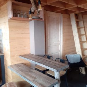 Cabane en bois moderne avec un mobilier en bois brut et des luminaires suspendus.