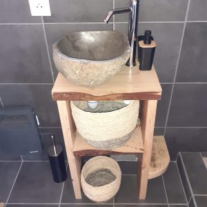 Élégant hébergement insolite avec lavabo en pierre et rangements en osier.