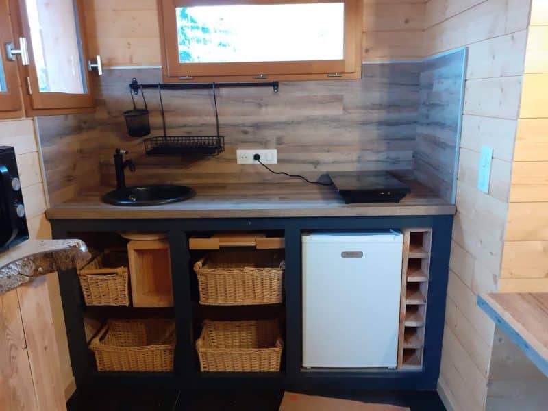 Cuisine moderne en chalet en bois, avec rangement en osier et réfrigérateur.