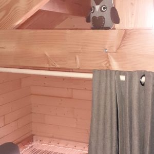 Cabane en bois avec une décoration chaleureuse et une chouette en peluche sur une poutre.