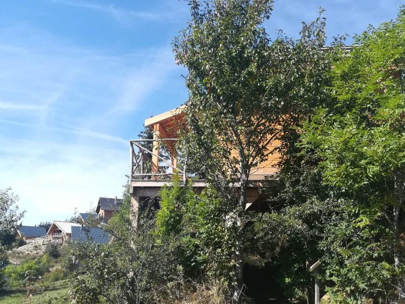Chalet en bois entouré de verdure, offrant une vue dégagée sur la nature.