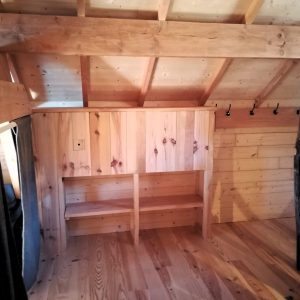 Cabane en bois dans les Alpes, avec un intérieur chaleureux et des poutres apparentes.